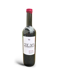 ラチャ地方のブドウ畑を背景に置かれた、Menabdeワイナリーのジョージアワインの赤ワインボトル