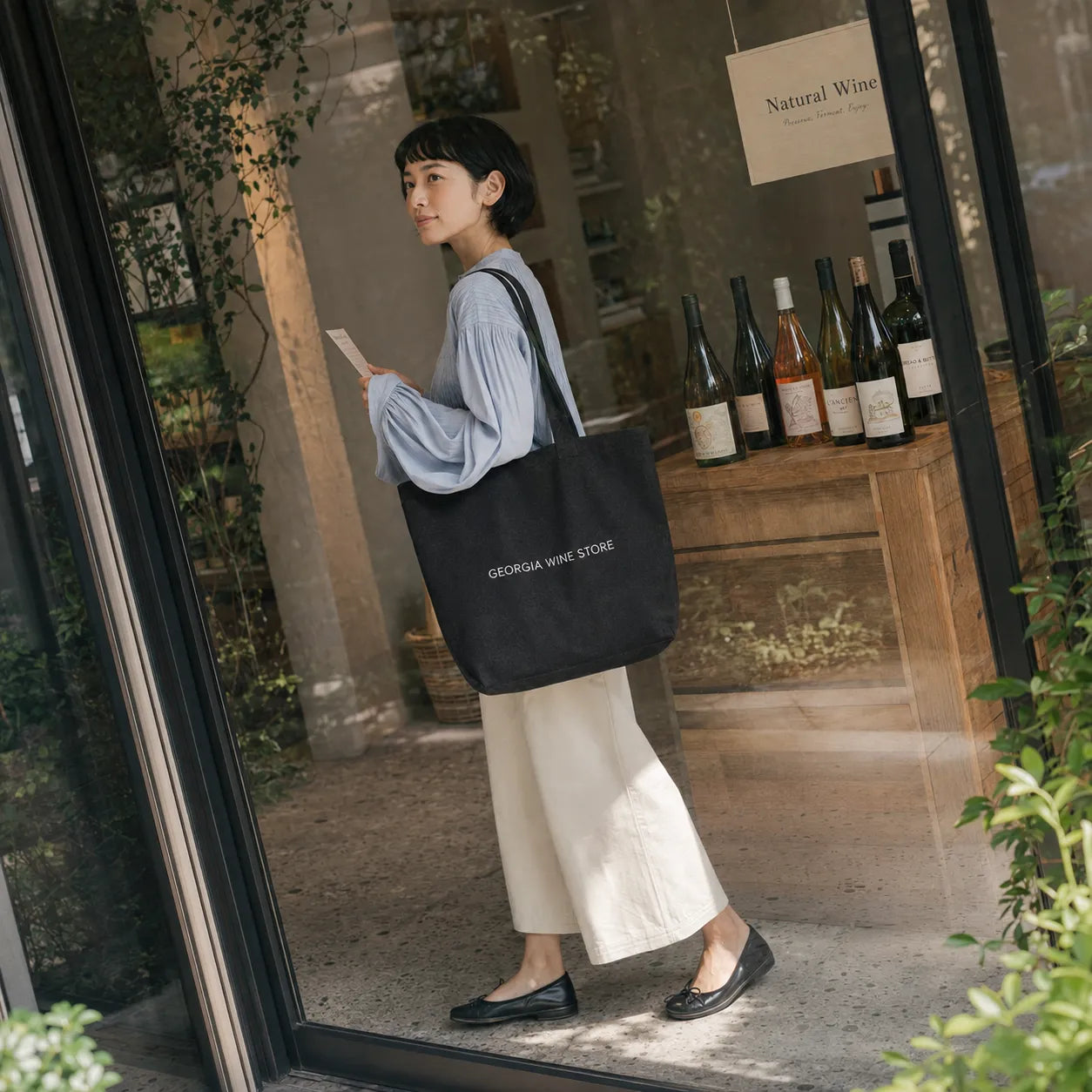 ブラックのトートバッグでナチュラルワインの店を訪れる女性、ガラス張りの店先